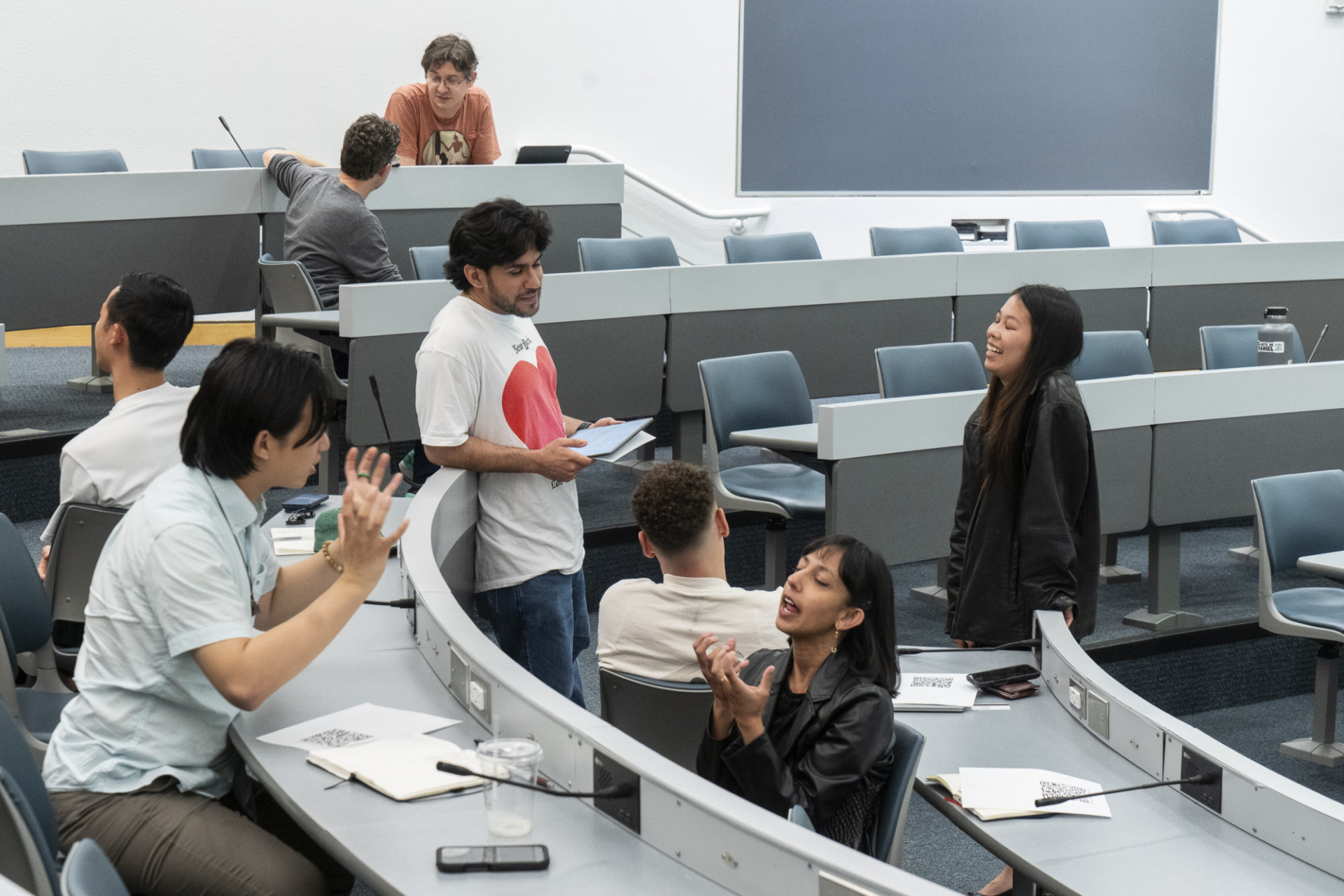 Students talk and collaborate in small groups in a lecture hall during "Faculty-Student Collaborations to Reimagine the University."